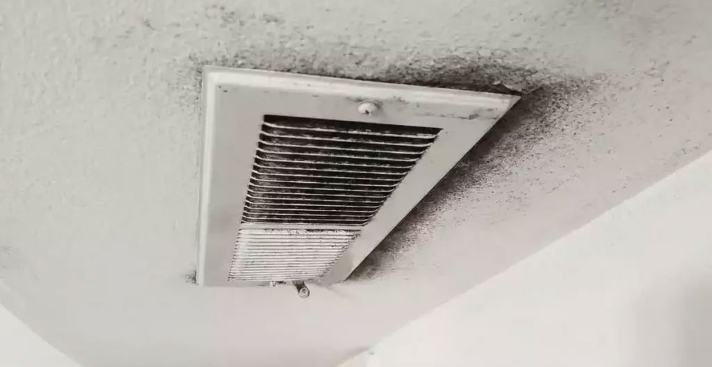 Ramoneur professionnel examinant des traces de suie autour d'une grille de ventilation